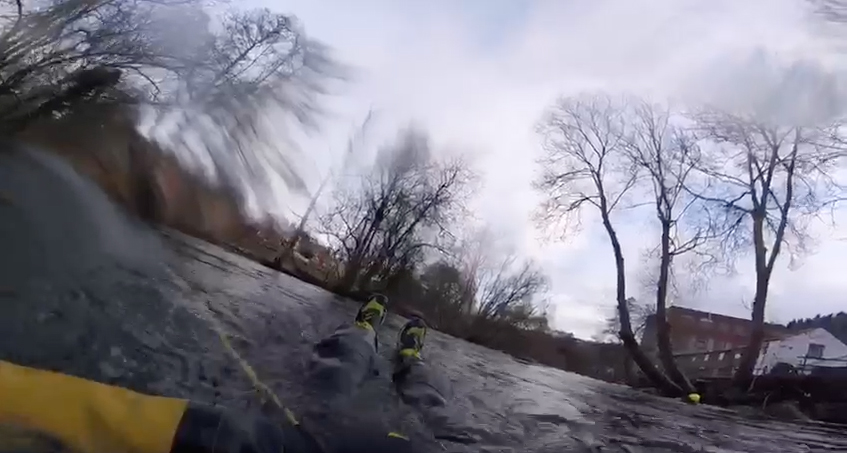 Station Manager Craig Jackson experiences what it is like to be in the fast flowing and flooded River Dee before a safety line is thrown to him from the river bank.