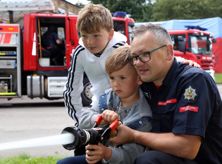 On Call firefighter Steve Breese shows Ethan and Matthew Breese how to use the fire hose at Wellington Fire Station’s annual open day.